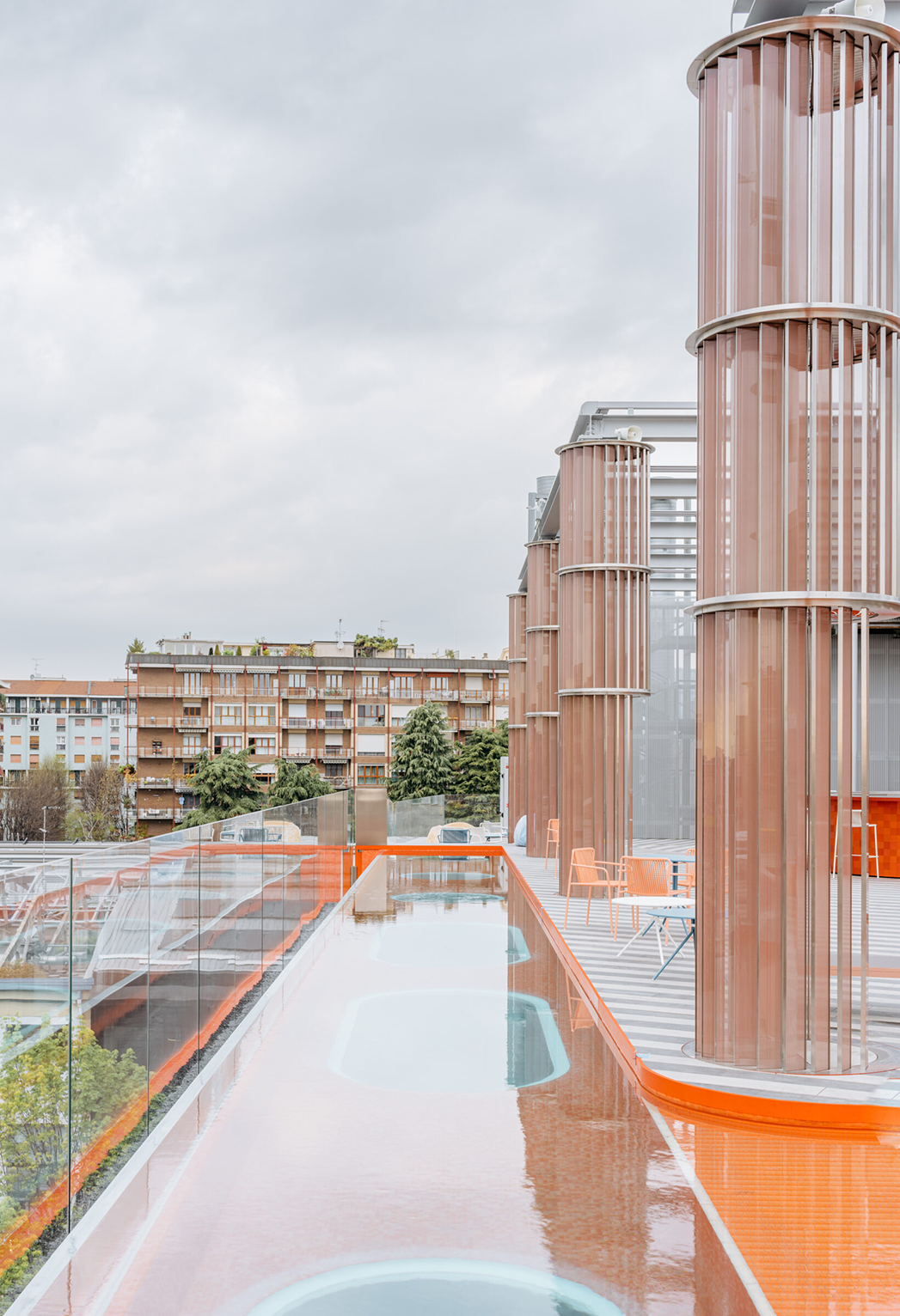 Terrazza Vertigo Pool a Milano con piscina a sfioro e iconiche colonne metalliche circolari dotate di alette frangisole verticali color rame, realizzate da Fratelli Gelmini.