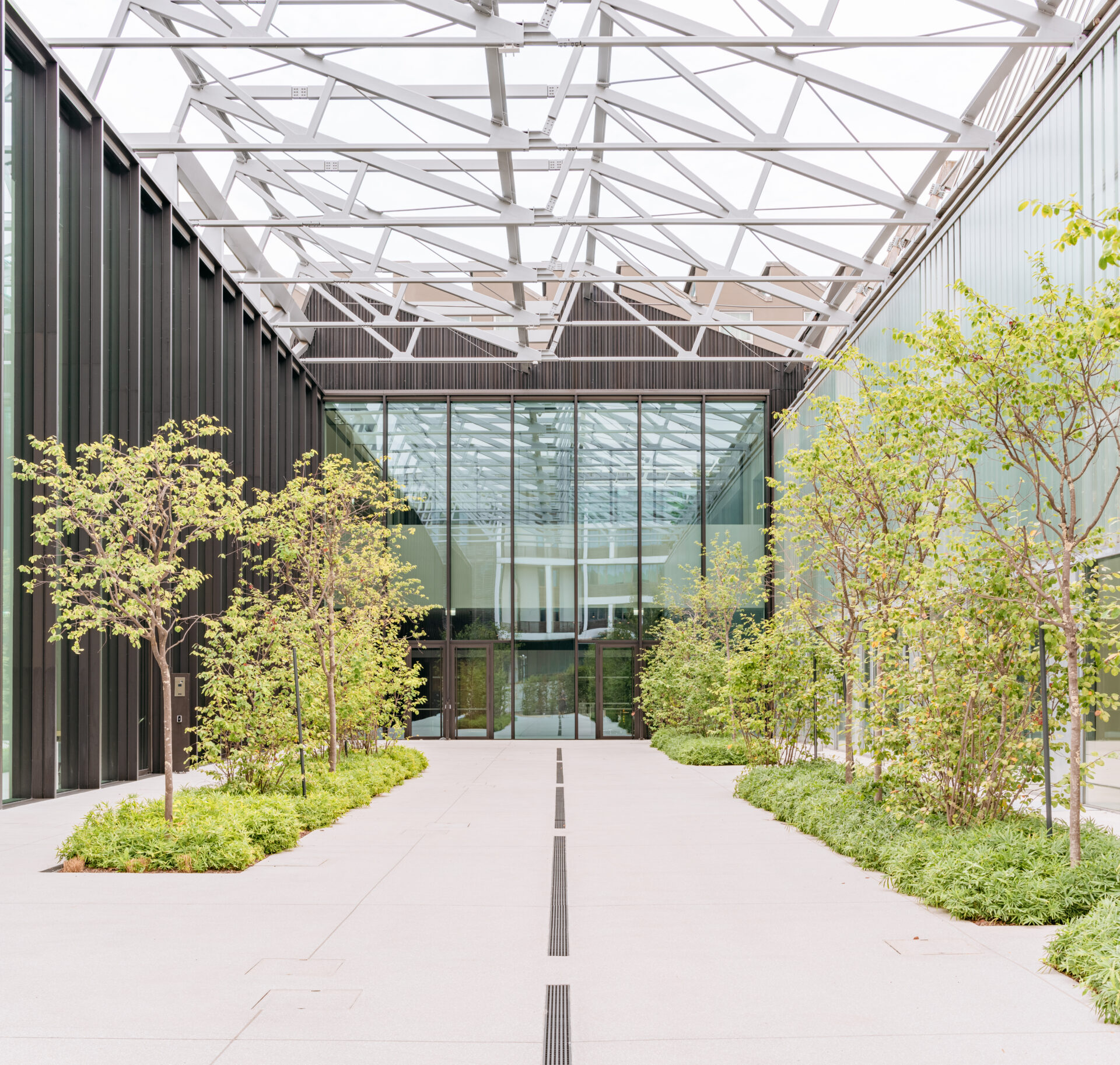 Atrio della Luxottica Digital Factory con grande copertura a capriate metalliche in acciaio zincato e vetro, carpenteria strutturale di Fratelli Gelmini.