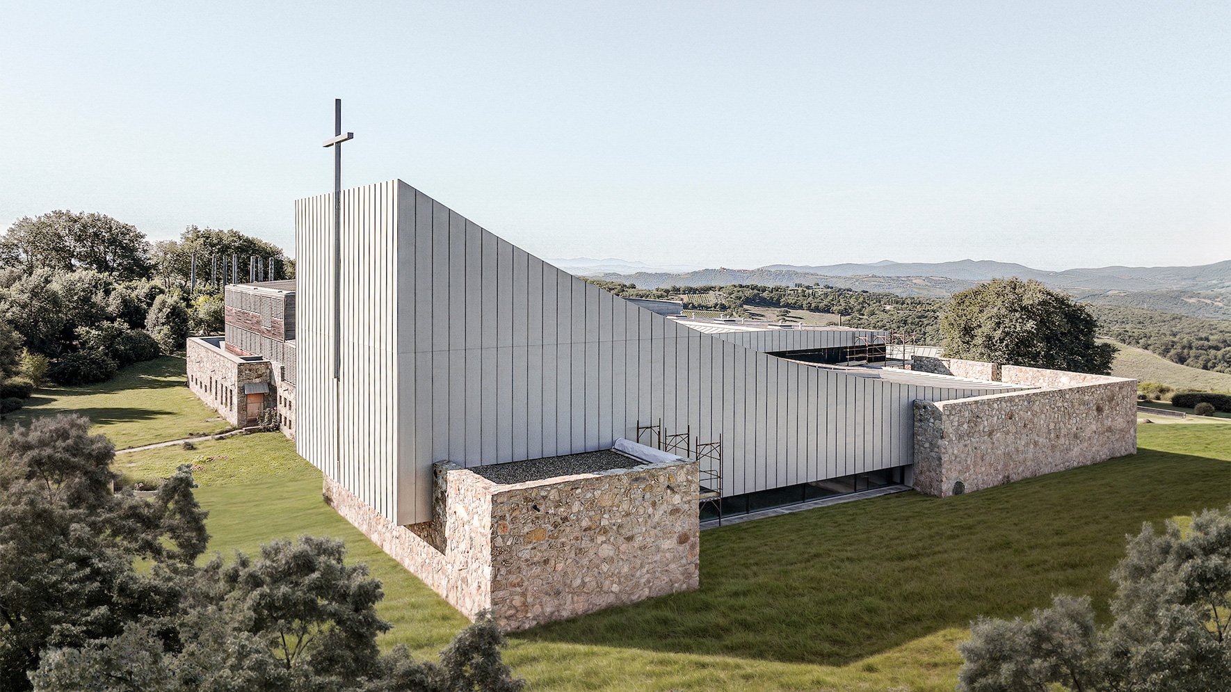 Edificio religioso contemporaneo con facciata in pannelli metallici e muratura in pietra. Progetto Monastero di Siloe realizzato da Gelmini, carpenteria strutturale in acciaio