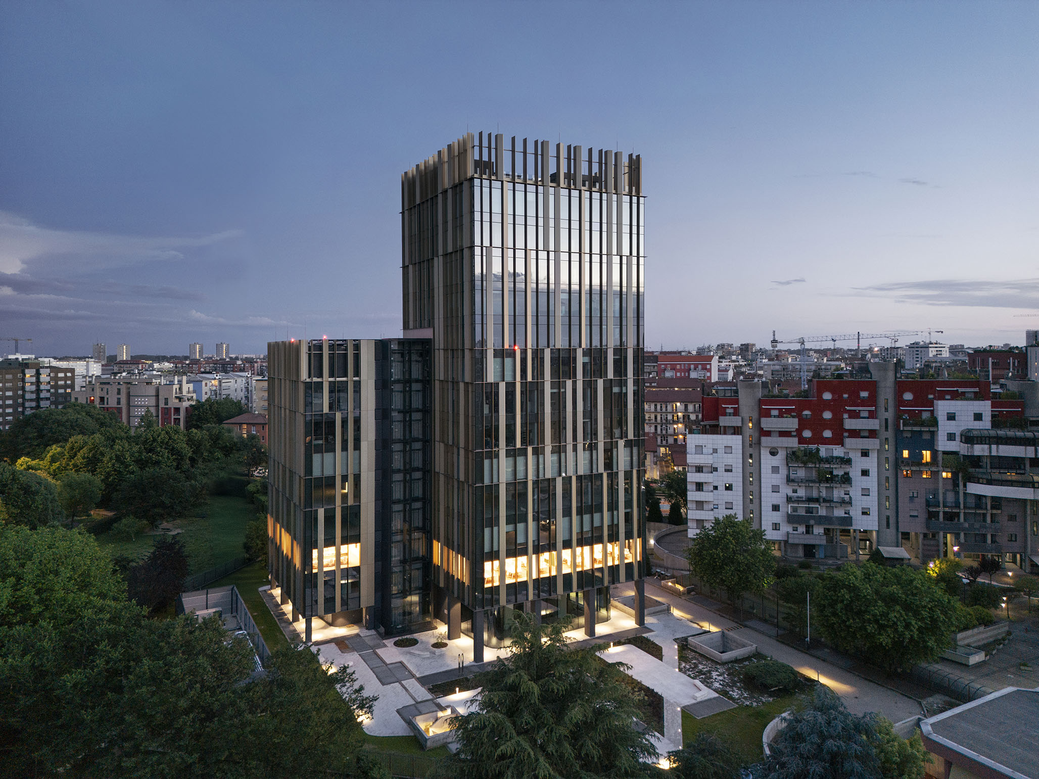 Vista aerea serale dell'edificio direzionale Nervesa 21 a Milano con lesene verticali e facciata in carpenteria metallica